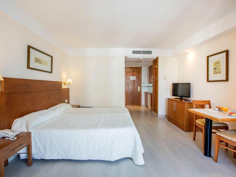 Bright hotel room with double bed, desk, TV, and modern amenities.