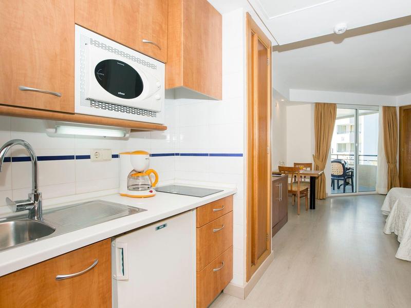 Compact kitchenette with microwave in a bright hotel room featuring dining area and balcony.