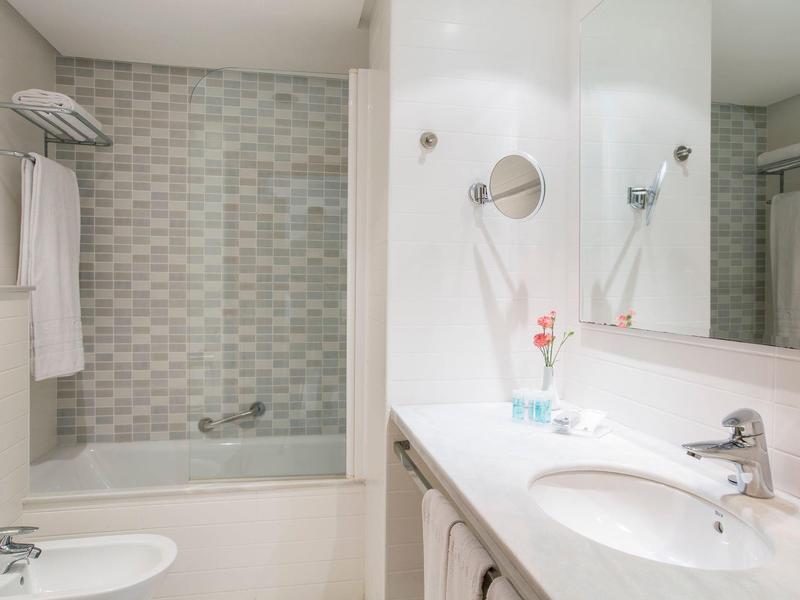 Modern bathroom with bathtub, sink, and large mirror.