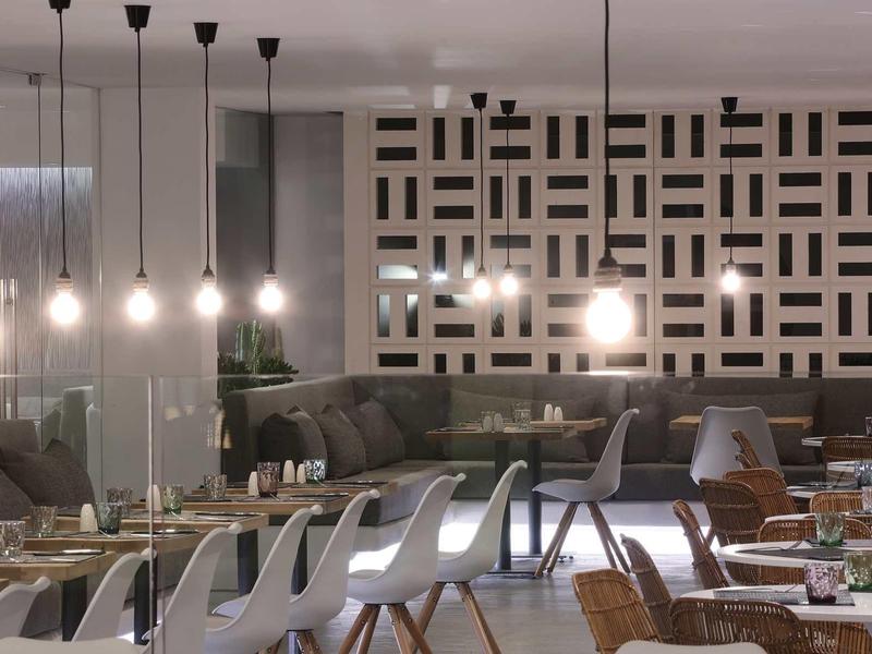 Nowoczesna restauracja z białymi krzesłami i stylowymi lampami wiszącymi na suficie.