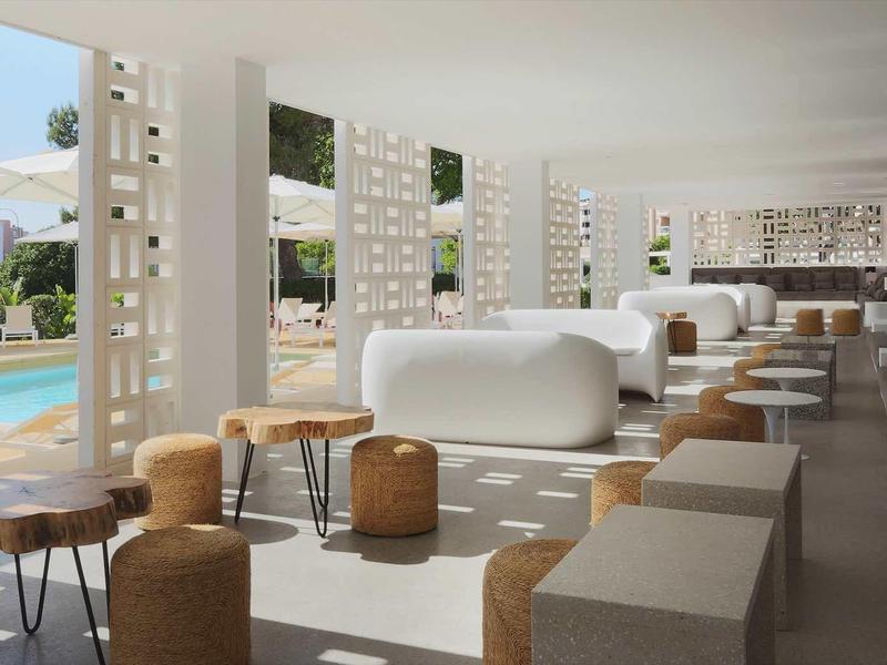 Nowoczesna, jasna część wypoczynkowa hotelu z widokiem na basen i góry.