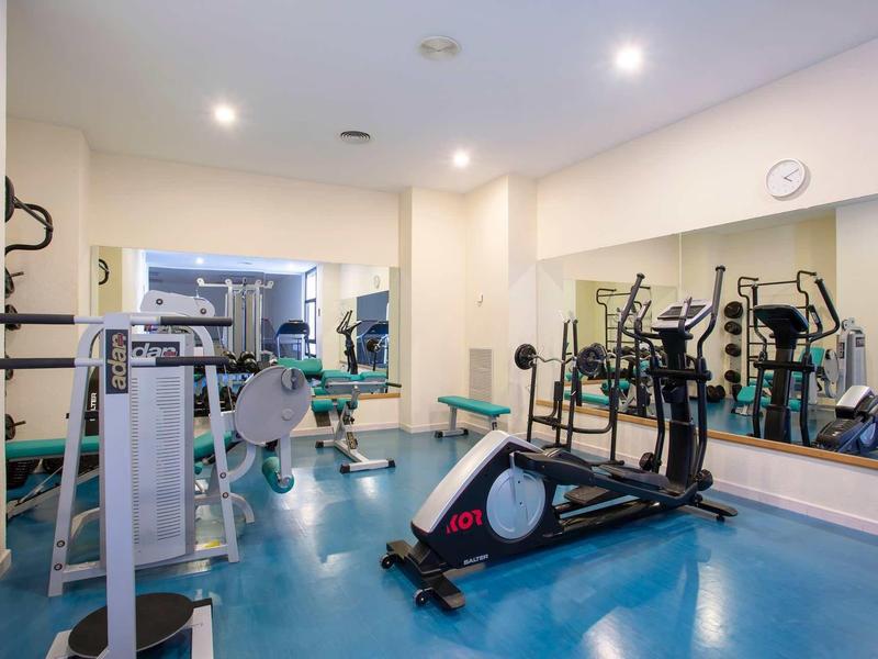 Gym room with various exercise equipment and a large wall mirror.