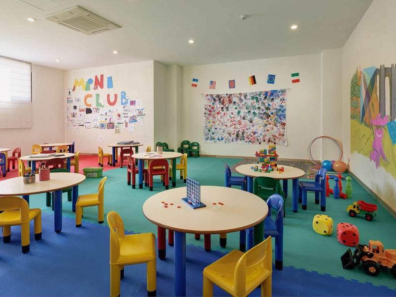 Colorful children's playroom with tables, bright chairs, and toys in a hotel