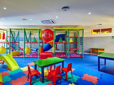 Barevná herna pro děti s překážkami, skluzavkou, stolem a židlemi.