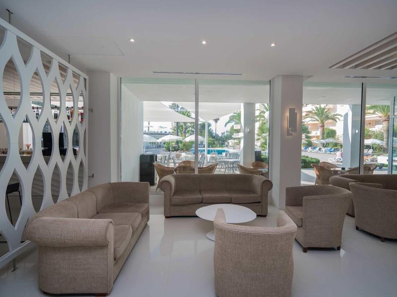 Moderní hotelový salonek s béžovými pohovkami a velkými okny na terasu.