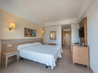 Habitación de hotel con dos camas individuales, muebles de madera y televisor en la pared.