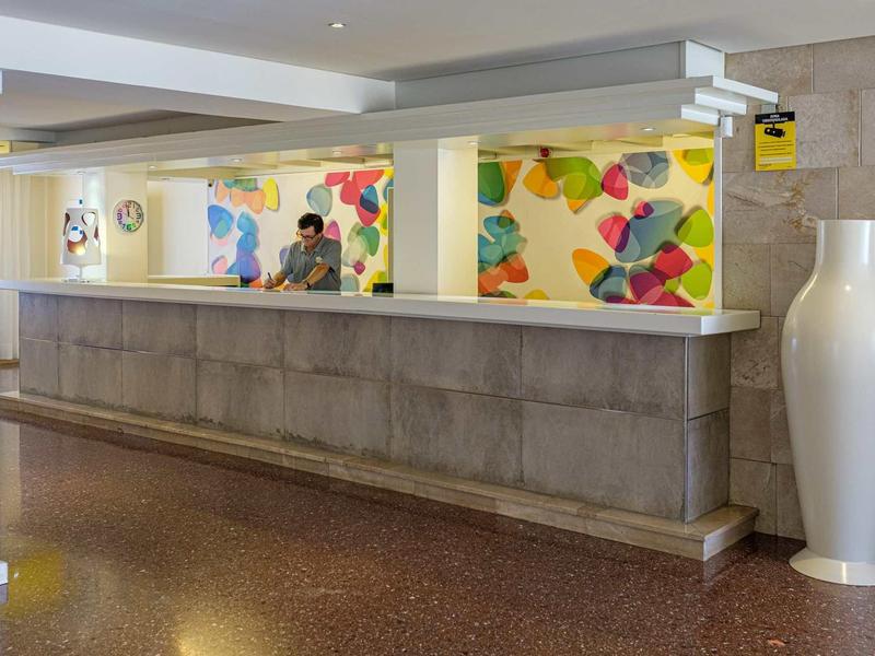 Modern hotel reception with colorful wall art and a large white vase.