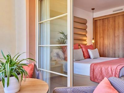 Modernes Schlafzimmer mit Holz- und Glasakzenten, Bett in Weiß und Rosa, grünpflanze auf Tisch.
