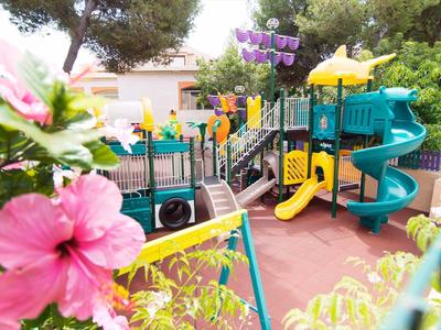 Bunter Kinderspielplatz mit Rutschen, Klettergerüsten und Blumen im Vordergrund.