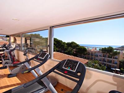 Fitnessraum mit Laufbändern vor großen Fenstern, die Ausblick auf Bäume und Gebäude bieten.