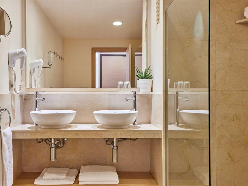 Světelná hotelová koupelna s dvojitými umyvadly a moderními armaturami