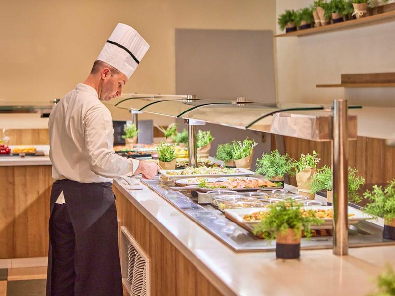 Kuchař u bufetu s různými saláty a pokrmy v hotelové restauraci.