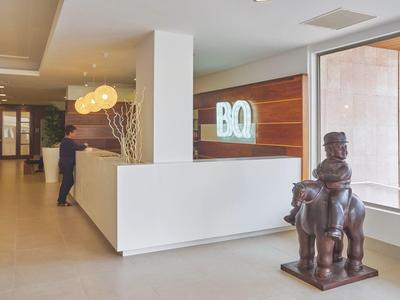 Recepción de hotel moderna con mostrador blanco y escultura artística junto a la ventana.