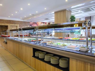 Área de buffet con ensaladas y platos en un restaurante de hotel moderno y luminoso.