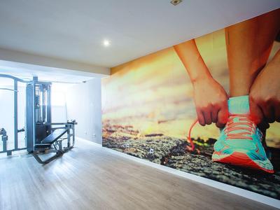 Palestra con attrezzatura e murale di persona che allaccia le scarpe da corsa.