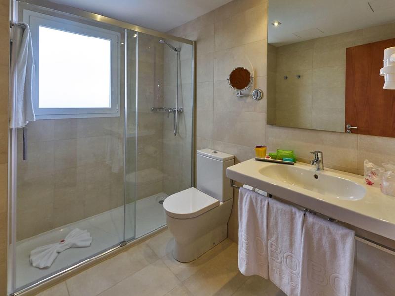 Baño moderno con ducha, inodoro, espejo grande y lavabo con cortina.