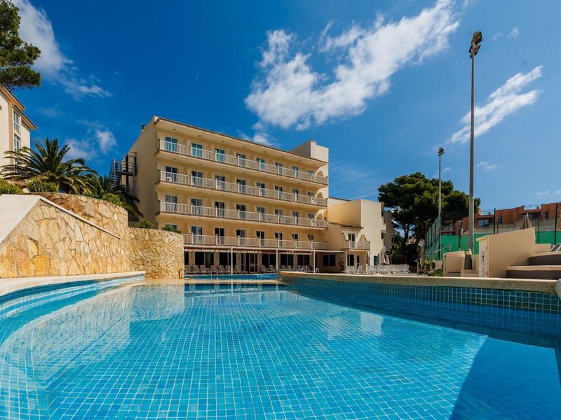 Edificio dell'hotel con grande piscina all'aperto sotto un cielo azzurro limpido.