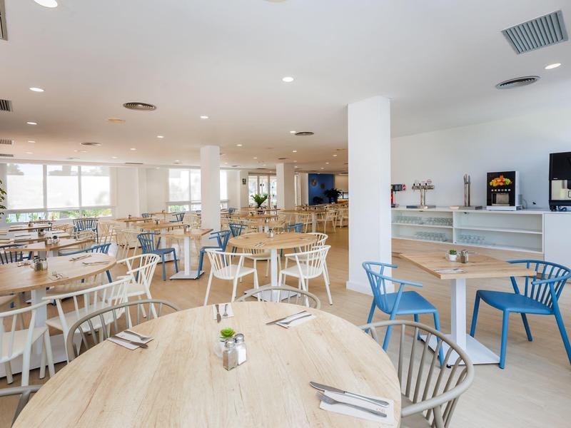 Sala colazione luminosa con tavoli moderni, sedie colorate e luce naturale.