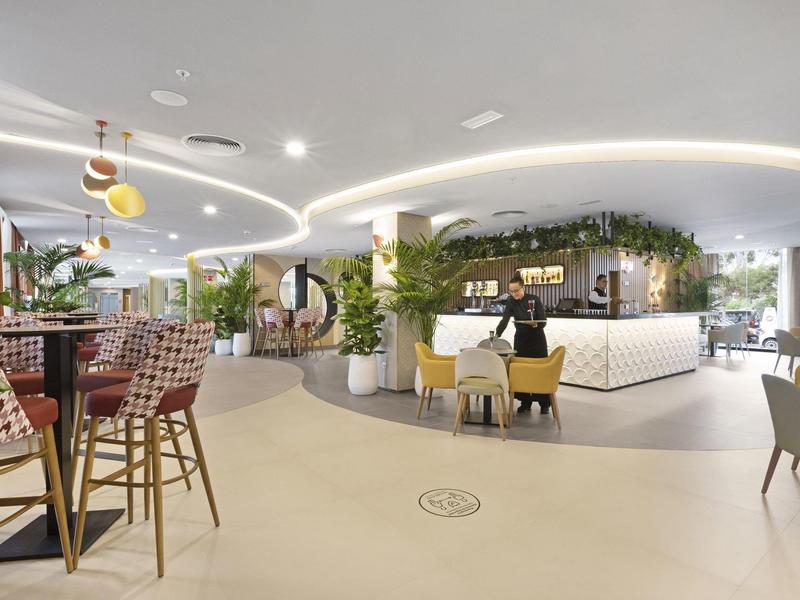 Restaurante moderno de hotel con asientos acogedores, plantas e iluminación elegante.