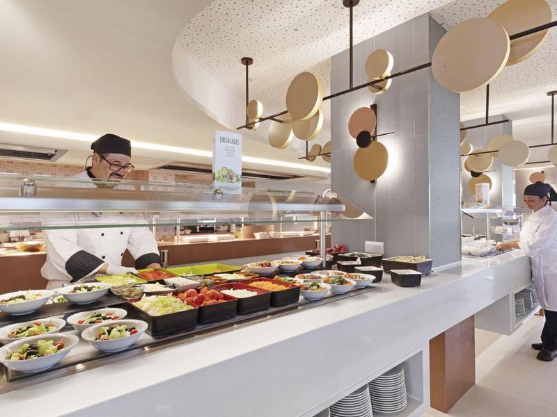 Cocina moderna de hotel con ingredientes frescos y personal de cocina con uniforme blanco.