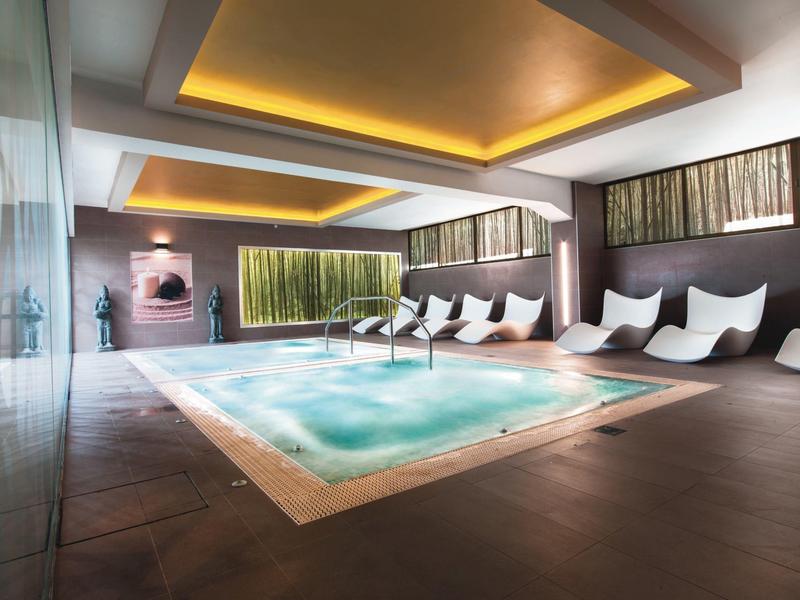 Moderní vnitřní jacuzzi s teplým osvětlením a elegantními lehátky.