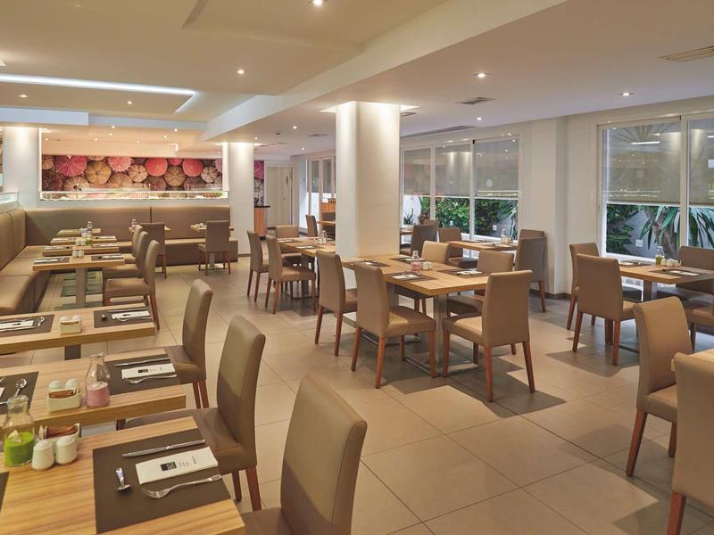 Jasna, nowoczesna restauracja z drewnianymi stołami i wygodnymi krzesłami, zachęcająca dla gości.