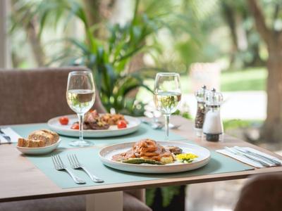Ein gedeckter Tisch mit zwei Tellern Pasta, Weingläsern und Brot in hellem, natürlichem Ambiente.