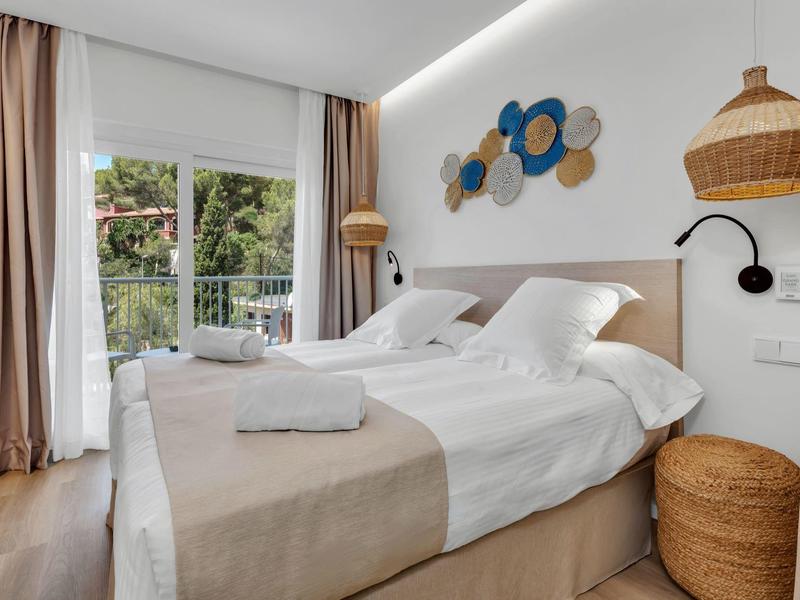 Pohodlný hotelový pokoj s dvojlůžkem, balkonem a nenápadnou nástěnnou dekorací.