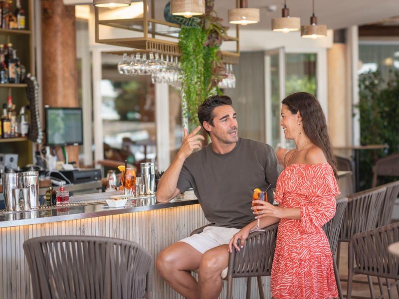 Pár odpočívá u baru v světlé, moderní hotelové restauraci.