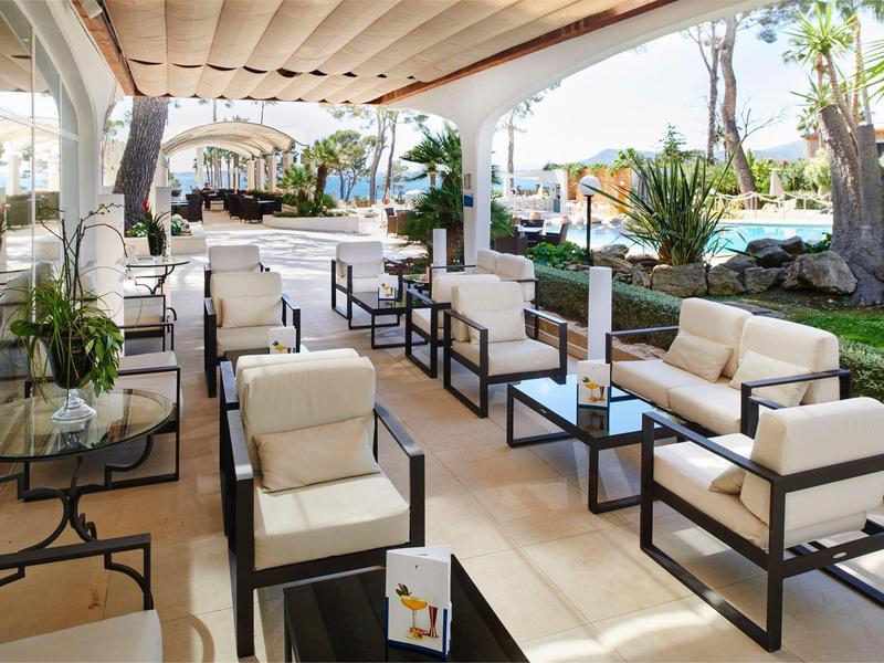 Elegantní venkovní lounge s pohodlnými křesly a výhledem na bazén za denního světla.