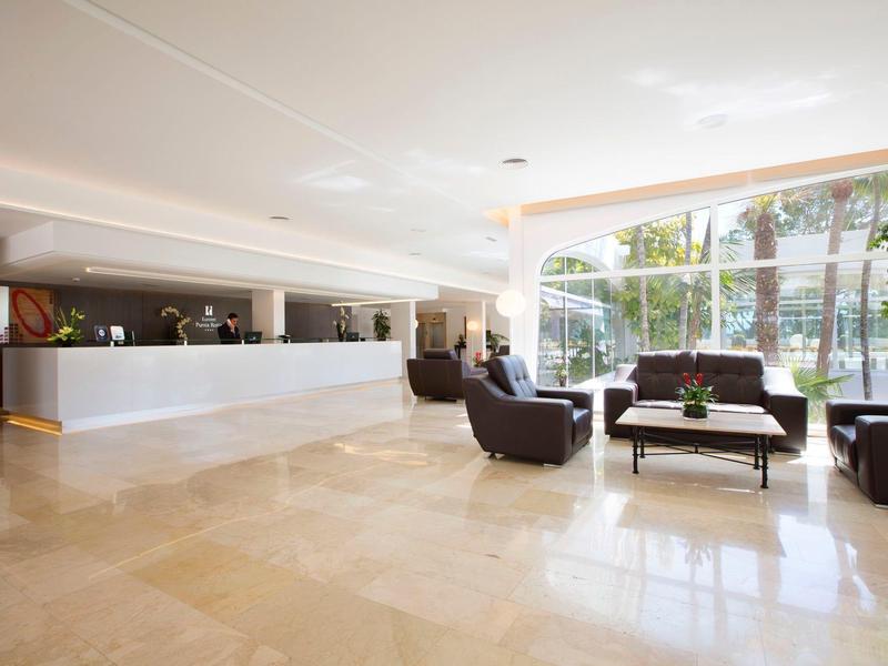 Prostorná hotelová lobby s posezením a velkými okny s výhledem ven.