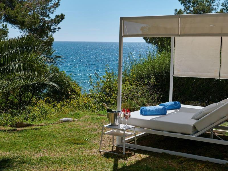 Lehátko s modrými ručníky pod stříškou u moře.