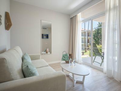 Bright living room with sofa, coffee table, and terrace view through large windows.
