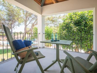 Covered balcony with garden table and chairs, view of green trees at the hotel