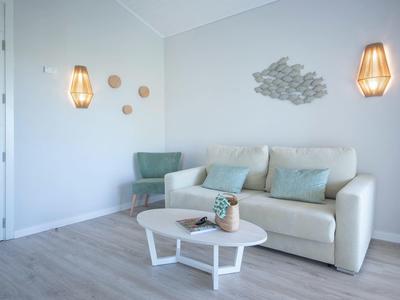 Bright modern living room with sofa, green armchair, table, and decorative wall lamps.
