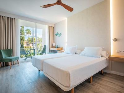 Bright hotel room with double bed, balcony, and modern furnishings