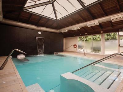 Interior space with swimming pool, wooden ceiling, and large windows letting in natural light.