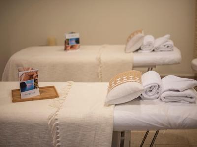 Two massage tables with white towels and warm lighting in a calm spa room.