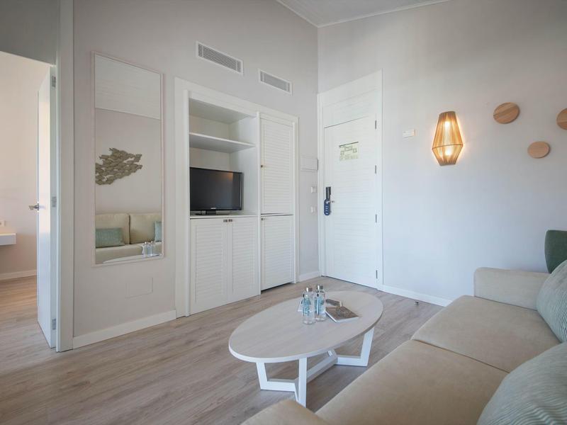 Bright hotel room with sofa, coffee table, and modern wall decor.