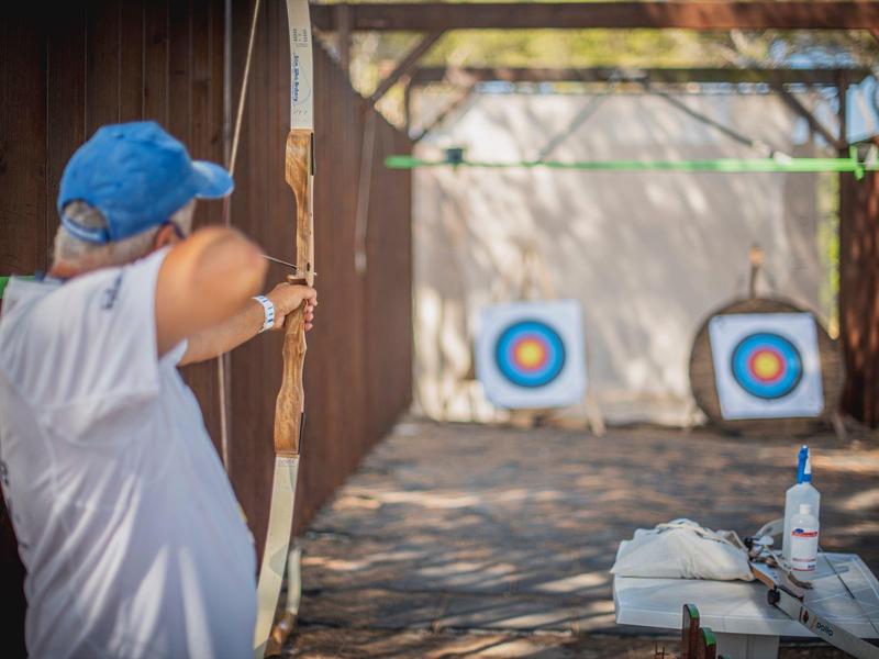 Person shooting with bow and arrow at targets outdoors on a sunny day