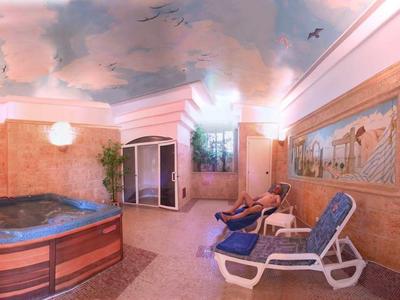Interior view of a wellness area with hot tub, lounge chairs, and relaxing atmosphere.