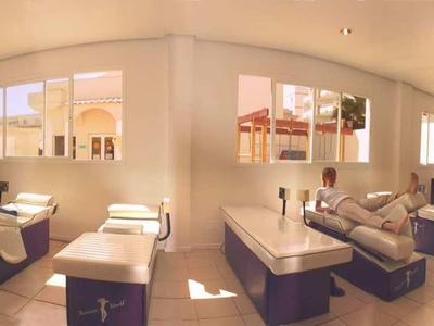 Großer, heller Fitnessraum mit verschiedenen Trainingsgeräten und Blick auf eine Terrasse.