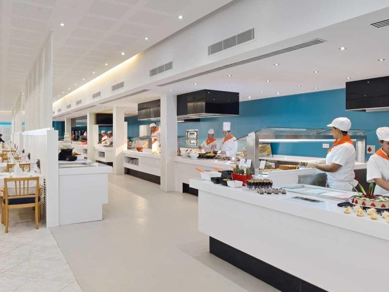 Buffet area in a modern hotel restaurant with chefs and guests.