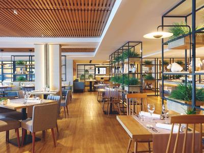 Modernes Restaurant mit Holzboden, gedeckten Tischen und grünen Pflanzen auf Metallregalen.