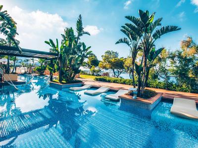 Un'area piscina invitante con lettini e piante tropicali in una giornata di sole.