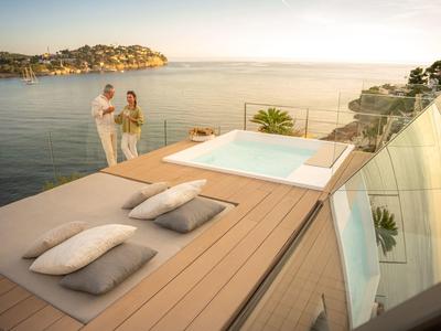 Luxuriöse Dachterrasse mit Whirlpool, Sonnendeck, zwei Kissen und Meerblick bei Sonnenuntergang.