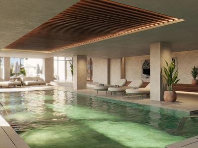 Moderner Innenpool mit Sonnenliegestühlen und pflanzen, ideal für Hotelgäste zum Entspannen.