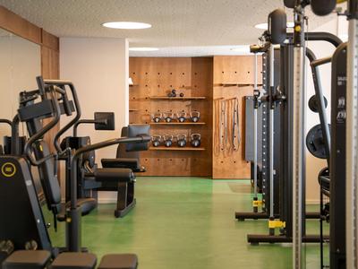Ein moderner Fitnessraum mit grüner Bodenfarbe und Holzpaneelen an der Wand.
