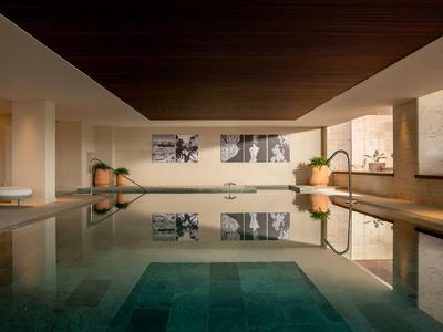Moderner Innenpool mit Holzdecke, weißen Wänden und großen Fenstern in einem Hotel.