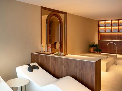 Moderner Wellnessbereich mit hellem Holz, Liegen und integriertem Whirlpool.